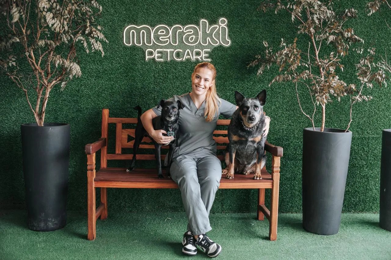 Veterinária da Meraki Pet Care sentada num banco com dois cachorros